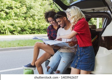 Multicultural group friends at open car back, looking map. Choose your road concept - Powered by Shutterstock