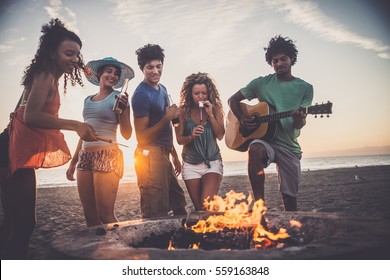 Multicultural group of friends partying on the beach - Young people celebrating during summer vacation, summertime and holidays concepts - Powered by Shutterstock