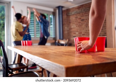 Multi-Cultural Group Of Friends Playing Game At Home Together Throwing Ball Into Plastic Cup