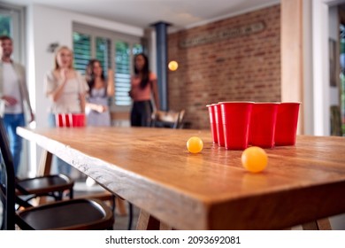 Multi-Cultural Group Of Friends Playing Game At Home Together Throwing Ball Into Plastic Cup