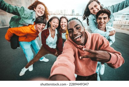 Multicultural group of friends taking selfie picture with smart mobile phone outside - Millenial people walking on city street - Life style concept with guys and girls hanging out together - Shutterstock ID 2289449347