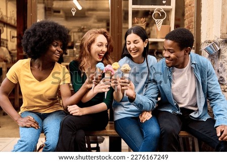 Multicultural group of friends toasting with colorful ice creams outdoors