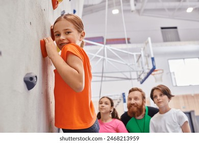 A multicultural group of kids standing together by a wall, listening attentively to their male teacher in a vibrant classroom. - Powered by Shutterstock