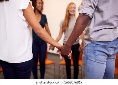 Multi-Cultural Group Of Men And Women Joining Hands At Mental Health Group Therapy Meeting