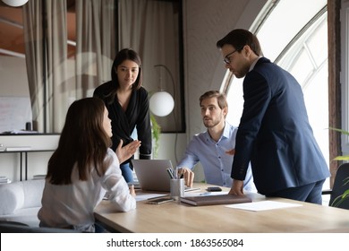 Multicultural group of millennial colleagues working in team having talk conversation discussion on formal meeting briefing, proposing financial strategy, comparing statistic data, analyzing results
