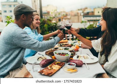 Multicultural group of people celebrating together having dinner party on rooftop, Best friends making cheers, drinking red wine enjoying healthy food at restaurant, Friendship Summer Party Concept - Powered by Shutterstock