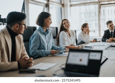 A multicultural group of people engaged in a collaborative business meeting in a contemporary office setting. Bright atmosphere with relaxed communication and teamwork in focus.