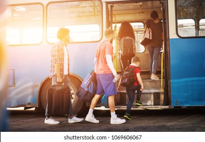 Multicultural group of people patiently entering the blue bus one by one while carrying their luggage.  - Powered by Shutterstock