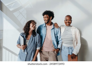 Multicultural group of professionals in modern office, male and female entrepreneurs, stand together smiling. Creative workforce showcases teamwork and collaboration in business casual setting. - Powered by Shutterstock