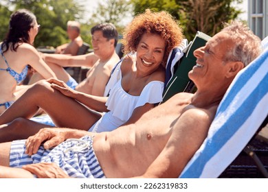 Multi-Cultural Group Of Senior Friends Relaxing On Sun Loungers By Outdoor Pool On Summer Vacation - Powered by Shutterstock