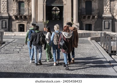 Multicultural group of students exploring historic university campus, engaged in educational tour