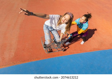 Multicultural Group Of Young Friends Bonding Outdoors And Having Fun - Stylish Cool Teens Gathering At Urban Skate Park, Shopping Cart Race And Fun