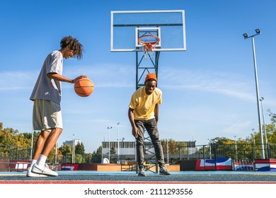 Multicultural group of young friends bonding outdoors and having fun - Stylish cool teens gathering at basketball court, 2 friends playing a match - Powered by Shutterstock