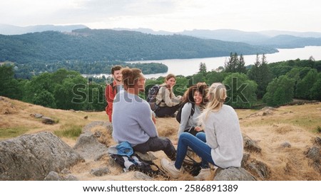 Multi-Cultural Group Of Young Friends Resting At Top Of Hill On Hike Through Lake District UK
