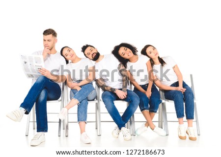 multicultural group of young people lying on shoulders of each other while man reading newspaper isolated on white