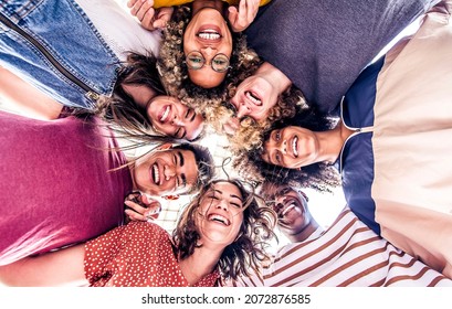 Multicultural Group Of Young People Standing In Circle And Smiling At Camera - Happy Diverse Friends Having Fun Hugging Together - Low Angle View	