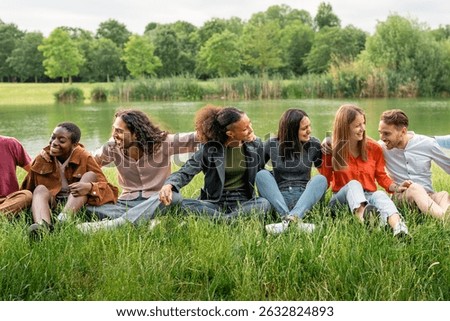 Multicultural group of young students sitting on the grass, building unity and sharing an authentic moment of connection and inclusion outdoors.