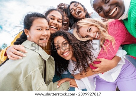Multicultural group of young women smiling at camera outdoors - Happy girl friends having fun together hanging out on city street - Female community concept with girls taking selfie picture with phone