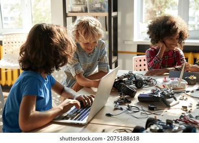 Multicultural happy diverse schoolchildren learning using gadgets and building robots on software robotics engineering class. Elementary school science classroom. STEM education concept. Cut image. - Powered by Shutterstock