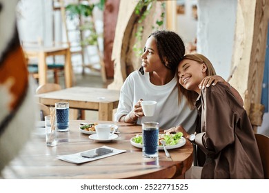 A multicultural lesbian couple smiles together at a cafe, enjoying breakfast and each others company. - Powered by Shutterstock