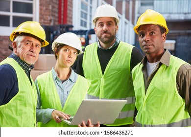 Multicultural Logistics Team With Laptop Computer In Front Of A Warehouse