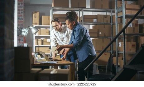 Multicultural Male and Female Warehouse Inventory Managers Talking, Using Laptop Computer and Checking Retail Stock. Rows of Shelves Full of Cardboard Box Packages in the Background. - Powered by Shutterstock