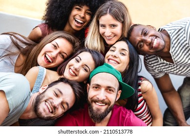 Multicultural men and women taking selfie outside - Happy milenial friendship and life style concept on young multiracial best friends having fun day together at urban city reunion - Warm vivid filter