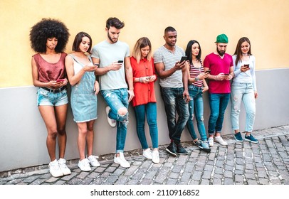 Multicultural milenials using smartphone against wall at university college backyard - Young students addicted by mobile smart phone - Technology concept with always connected millenials - Warm filter