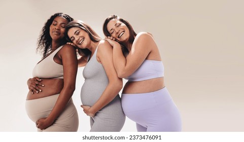 Multicultural pregnant women in fitness clothing attend a prenatal yoga class, leaning on one another for support. Happy and smiling, they prioritize self-care and wellbeing during their pregnancy. - Powered by Shutterstock