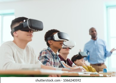 Multicultural schoolchildren using virtual reality headsets and african american teacher standing behind - Powered by Shutterstock