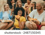 Multicultural smiling friends eating pizza sitting outside - Cheerful young people enjoying summer vacation together - Happy life style concept with guys and girls hanging out on a sunny day