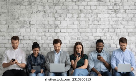 Multicultural team of gadget users sitting in line, using laptops, tablets, mobile phones, working, reading messages, chatting online on social media, watching content on internet. Copy space - Powered by Shutterstock