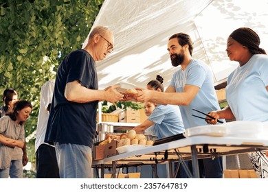 Multicultural team of humanitarian aid workers at food drive, sorting through donated food to ensure efficient distribution to less fortunate. Handing out of free meals to people in poverty. - Powered by Shutterstock