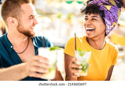 Multicultural trendy couple having fun drinking cocktails at beach party - Summer joy and life style concept with young people at festival happy hour - Warm bright filter with focus on right woman - Powered by Shutterstock