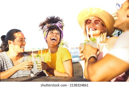 Multicultural trendy friends having fun drinking cocktails at sunset beach party - Summer joy and life style concept with young people at chiringuito happy hour - Warm filter with focus on left woman