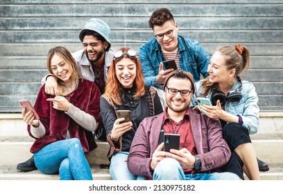 Multicultural urban friends having fun on mobile phone at urban place - Young happy guys and girls sharing time together watching funny video on smartphone - Contrast filter with focus on middle woman