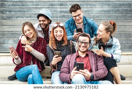 Multicultural urban friends having fun on mobile phone devices at grungy place - Young happy guys and girls sharing time together watching trendy funny video on smartphone - Bright contrast filter