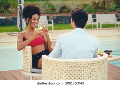 Multicultural Young Couple Sitting Poolside At A Table - Romanic Young People Eating Fruit For Breakfast By The Resort Swimming Pool - Healthy Lifestyle And Travel Concept