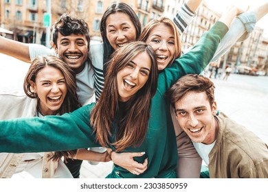 Multicultural young people smiling at camera outside - Millenial friends having fun hanging on city street - Friendship concept with guys and girls enjoying day out together - Youth community concept - Powered by Shutterstock