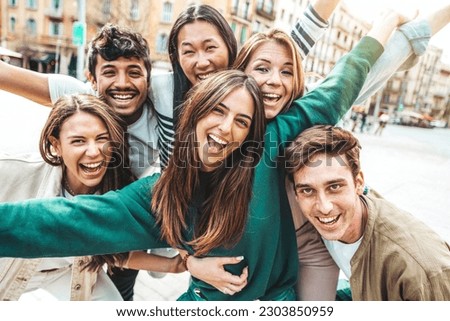 Multicultural young people smiling at camera outside - Millenial friends having fun hanging on city street - Friendship concept with guys and girls enjoying day out together - Youth community concept