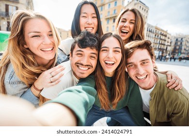 Multicultural young people smiling together at camera outside - Happy group of friends taking selfie pic walking on city street - Friendship concept with guys and girls enjoying sunny day in downtown