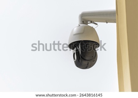 A multi-directional security camera system mounted on a pole, featuring a dome camera and two bullet cameras, under an overcast sky for surveillance.