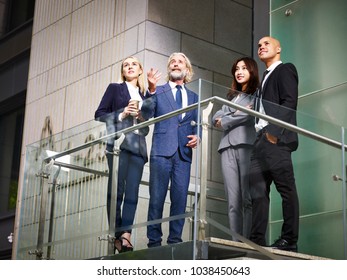 multiethnic architects examining and inspecting structure of modern building,  low angle view.