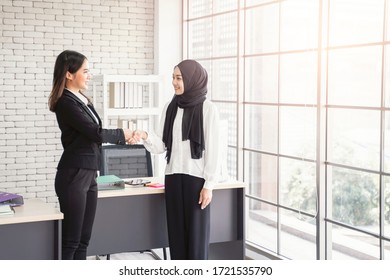 multiethnic asian female muslim working in office as team smiling happy shaking hands on agreement of planning strategy, concept diversity of different culture race type of people co-working together