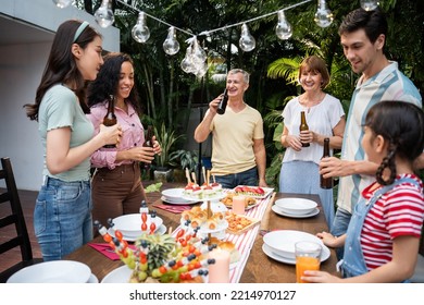 Multi-ethnic Big Family Having Fun, Enjoy Party Outdoors In The Garden. Attractive Diverse Group Of People Having Dinner, Eating Foods, Celebrate Weekend Reunion Gathered Together At The Dining Table.