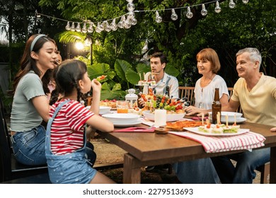 Multi-ethnic big family having fun, enjoy party outdoors in the garden. Attractive diverse group of people having dinner, eating foods, celebrate weekend reunion gathered together at the dining table. - Powered by Shutterstock