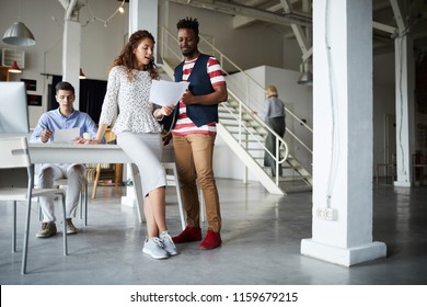 Multiethnic business couple examining document with other people working at modern office - Shutterstock ID 1159679215