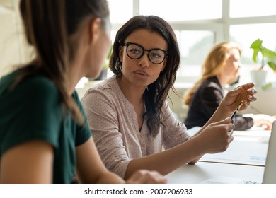 Multiethnic business coworkers discussing startup project. Mixed race mentor training young student, intern, explaining task. Two diverse team members working together, talking at workplace - Shutterstock ID 2007206933