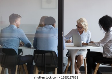 Multi-ethnic business people accomplish important negotiations with contract signing, company representatives and client sitting behind closed doors at modern boardroom, view through the glass wall - Powered by Shutterstock