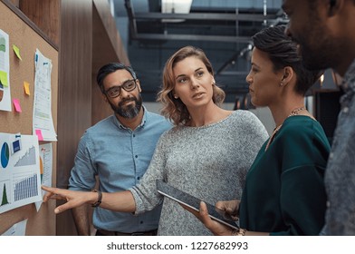 Multiethnic Business People Discussing Charts And Graphs Showing The Results Of Their Successful Teamwork. Mature Business Woman Showing Presentation To Casual Colleagues In During Night Meeting.